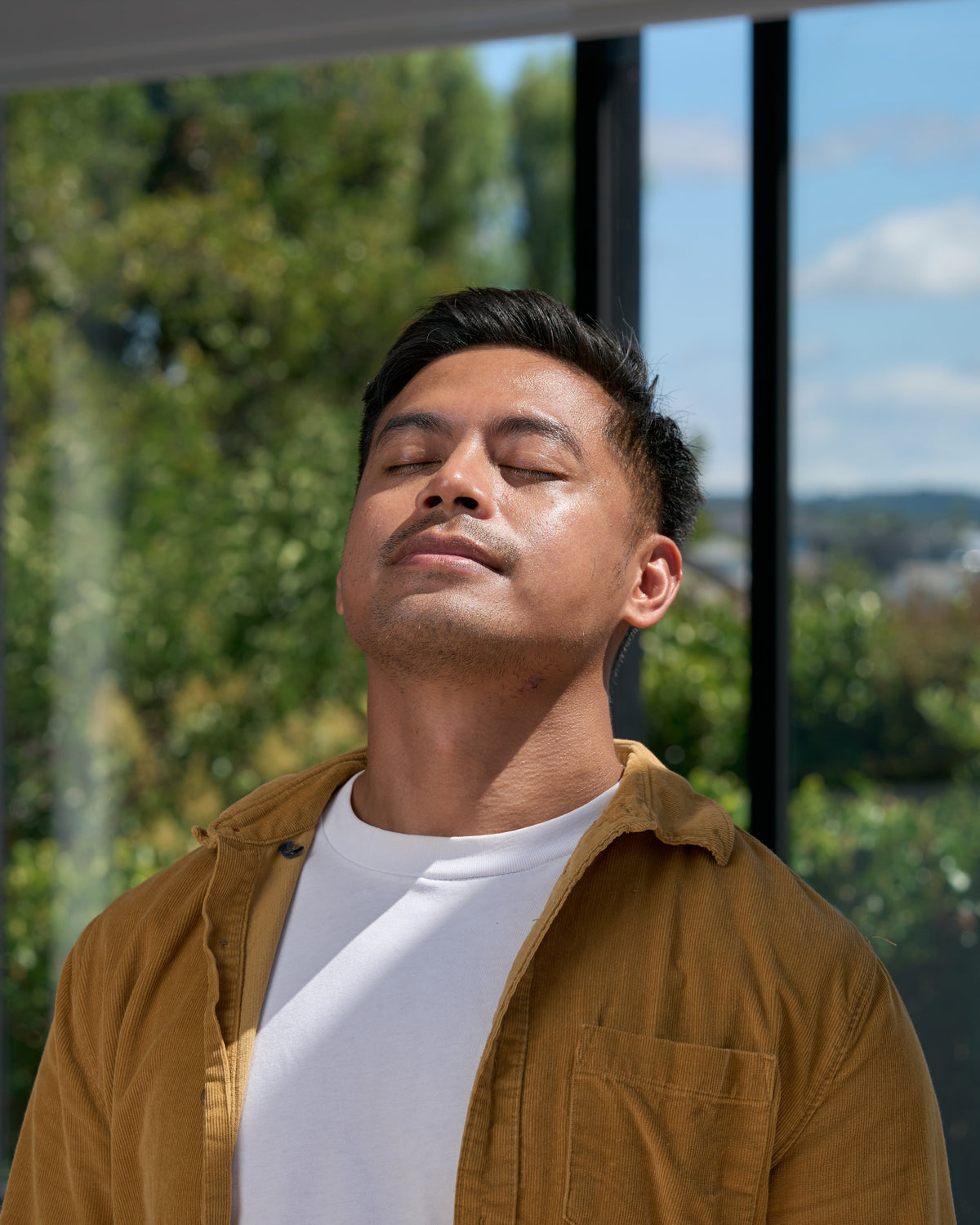 Man with eyes closed breathing through his nose in a bright, natural setting